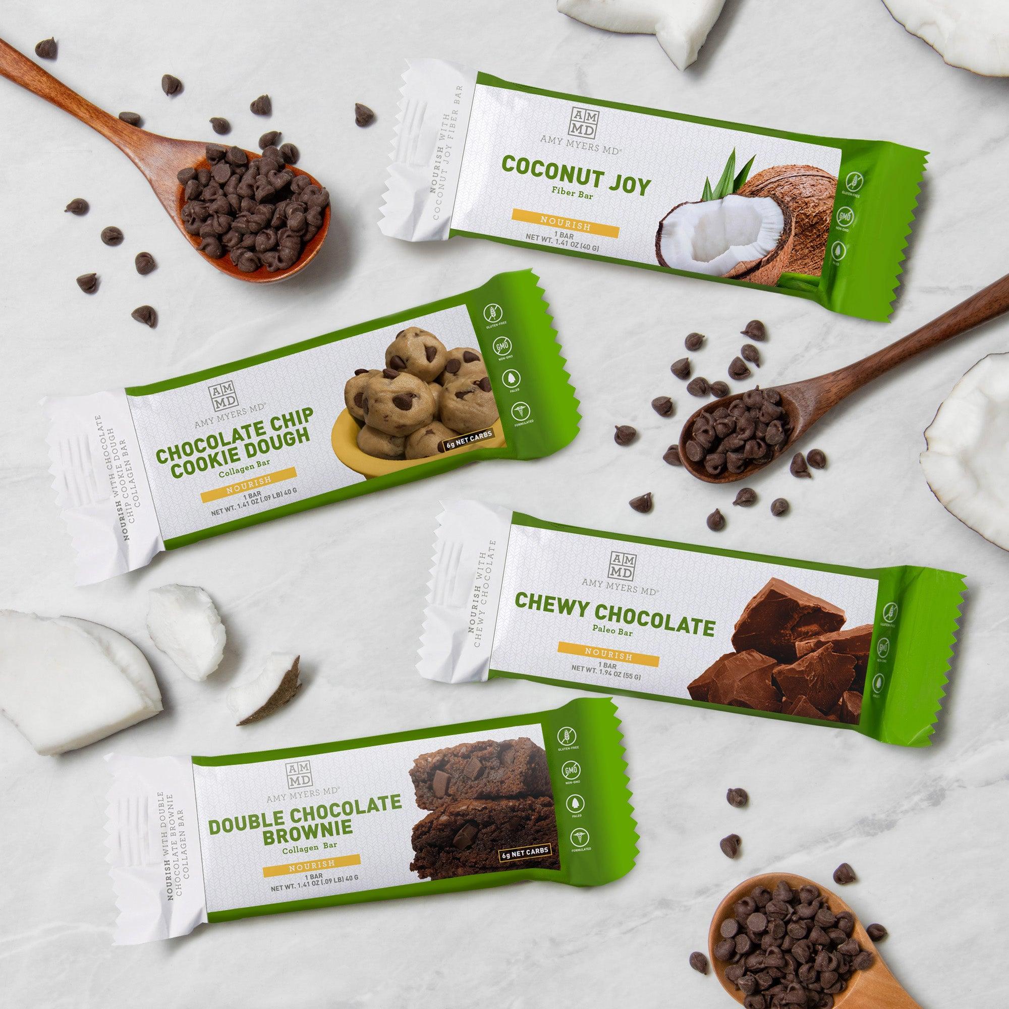 The 4 Bar Sampler Pack includes all 4 bars, each sitting on a white kitchen counter. Top to bottom: Coconut Joy Fiber Bar, Cookie Dough Collagen Protein Bar, Chewy Chocolate Paleo Bar, and Double Chocolate Brownie Collagen Protein Bar.