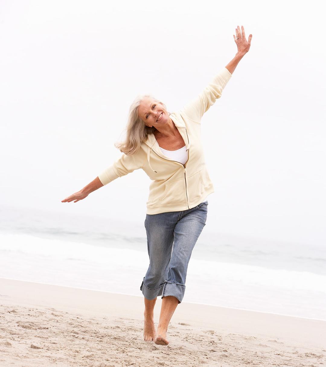 Woman walking on the beach looking joyful.