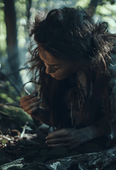 Primitive woman scavenging for food in a forest.