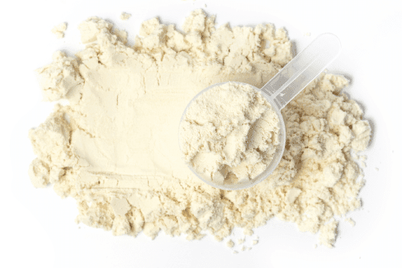 A scoop of Vanilla Bean Paleo Powder from a pile.