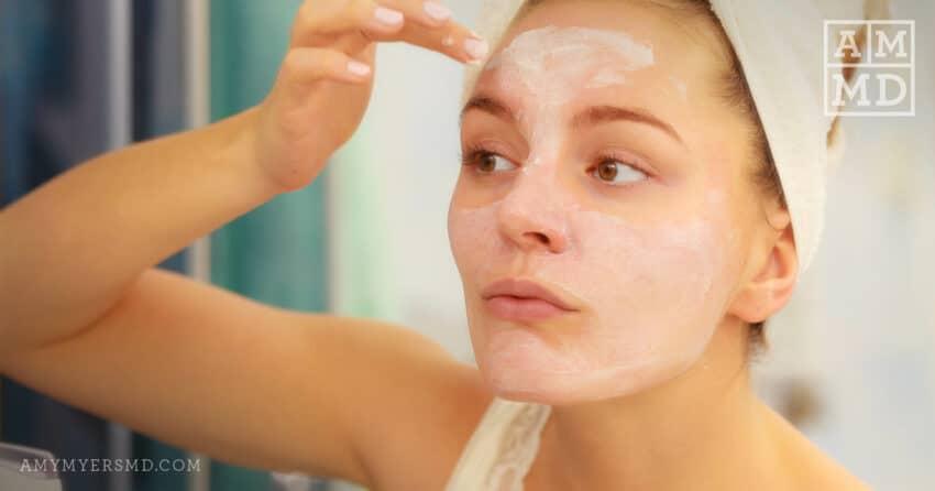 A woman applying a facial mask.