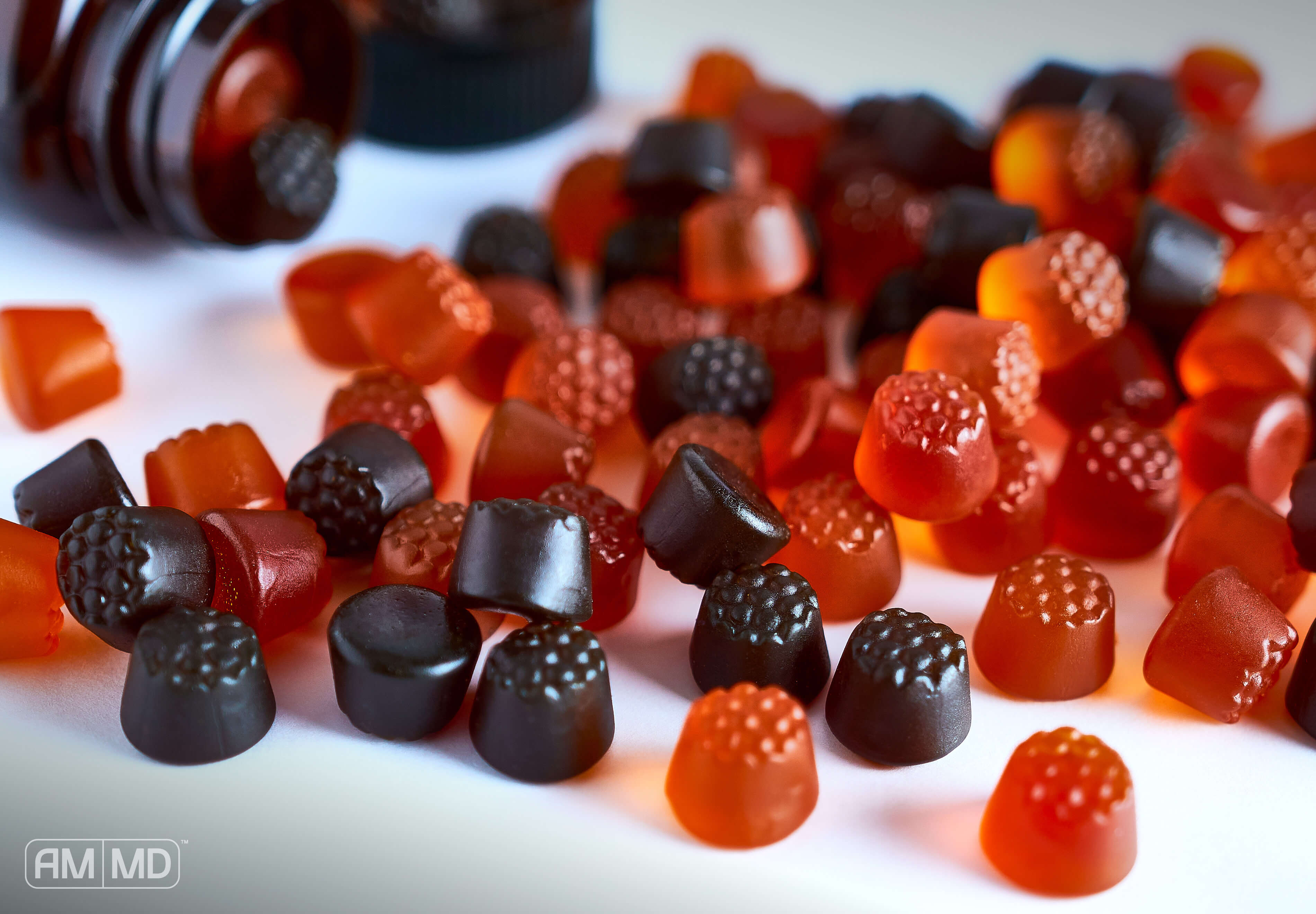 bottle with gummies pouring out on to table - AMMD