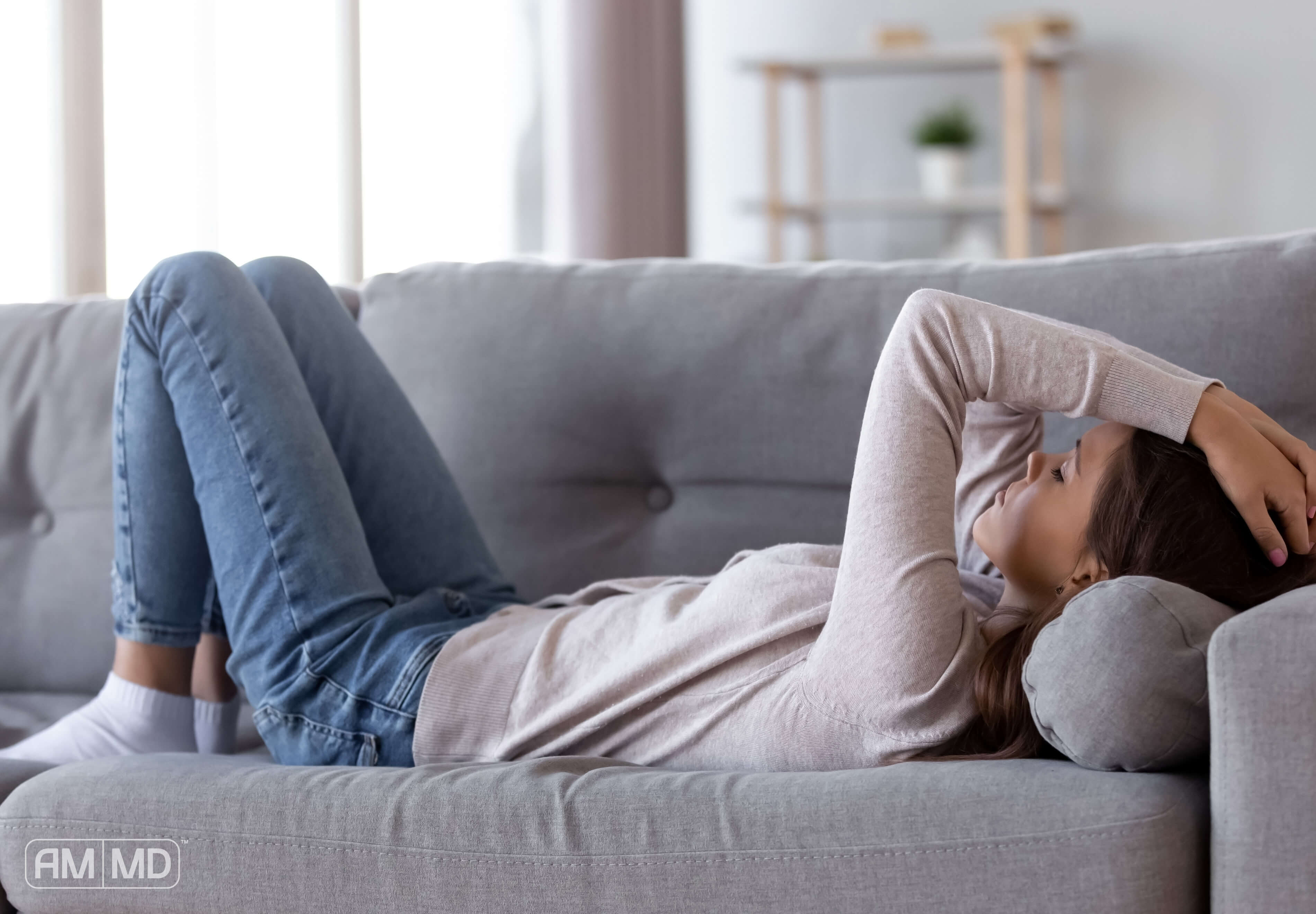 Woman laying on couch clutching head - Mercury Overload - Amy Myers MD®