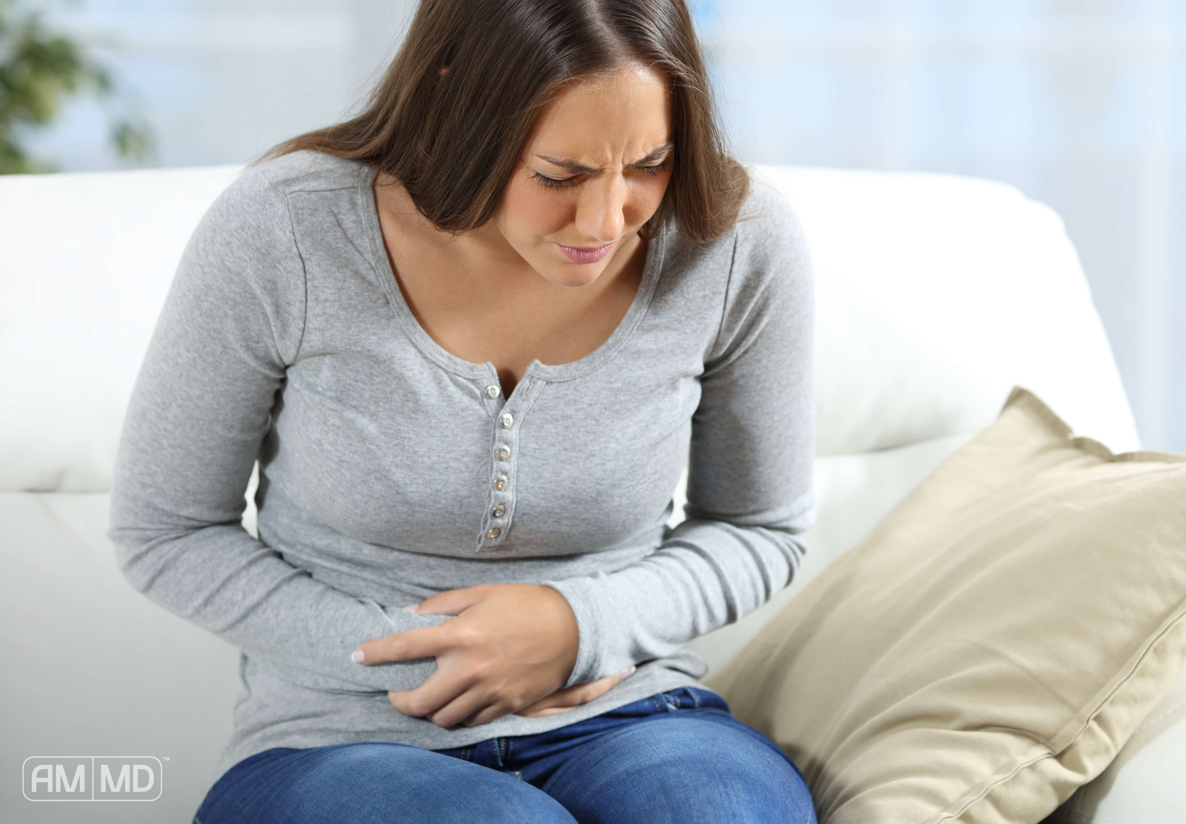 	Woman clutching her abdomen in pain depicting symptoms of chronic constipation and gut dysfunction