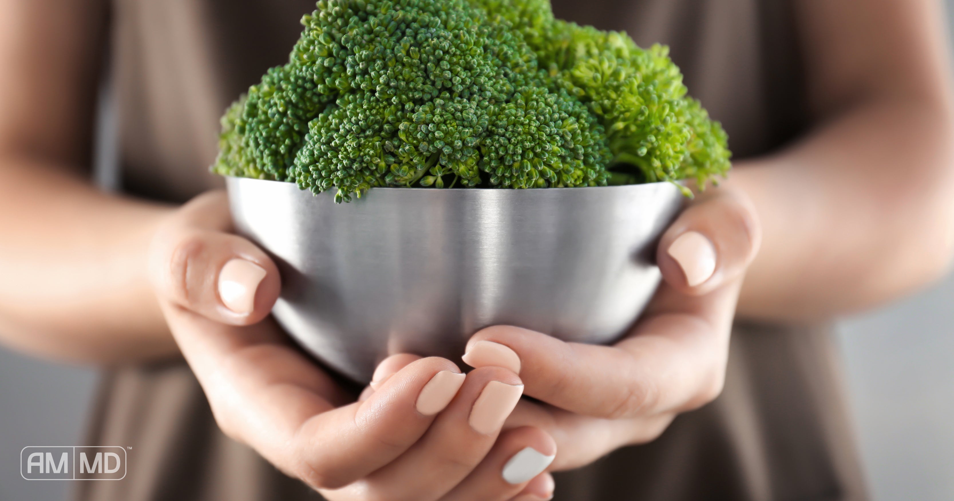 Woman holding bowl of broccoli - 9 Foods to Eat for Brain Health - AMMD™