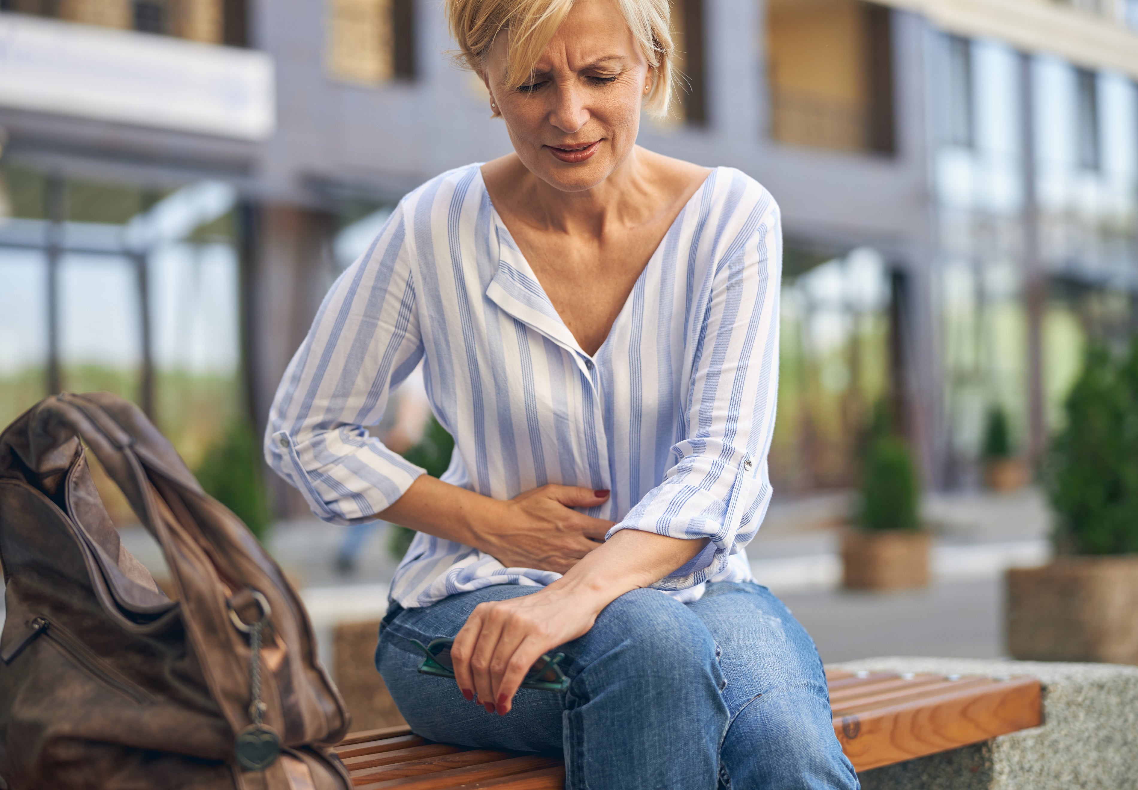 9 Symptoms of Leaky Gut & What To Do - Woman suffering from digestive discomfort - AMMD™