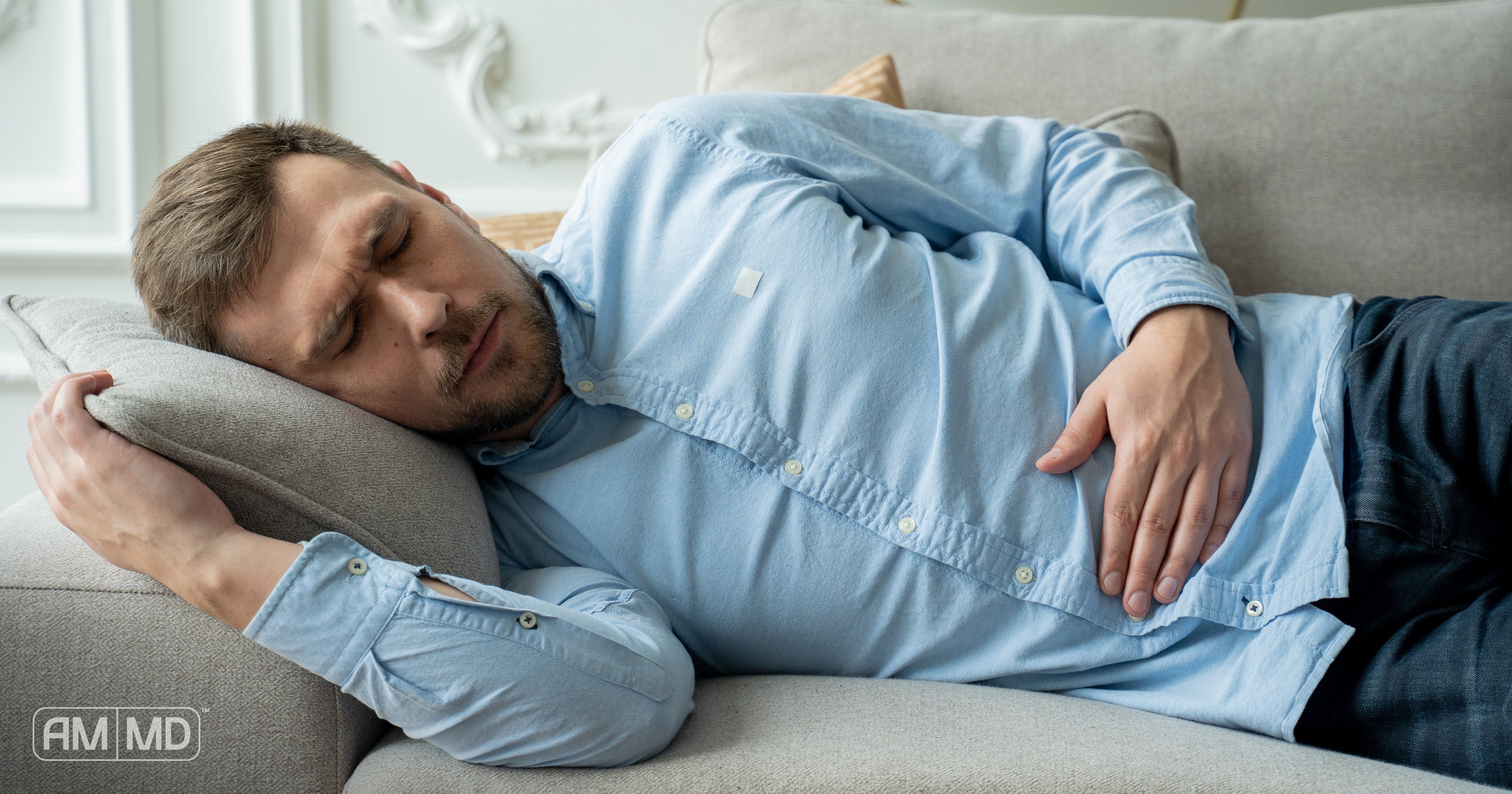 Man laying on couch holding stomach - Men’s Gut Health: The 4 Most Common Problems - AMMD™