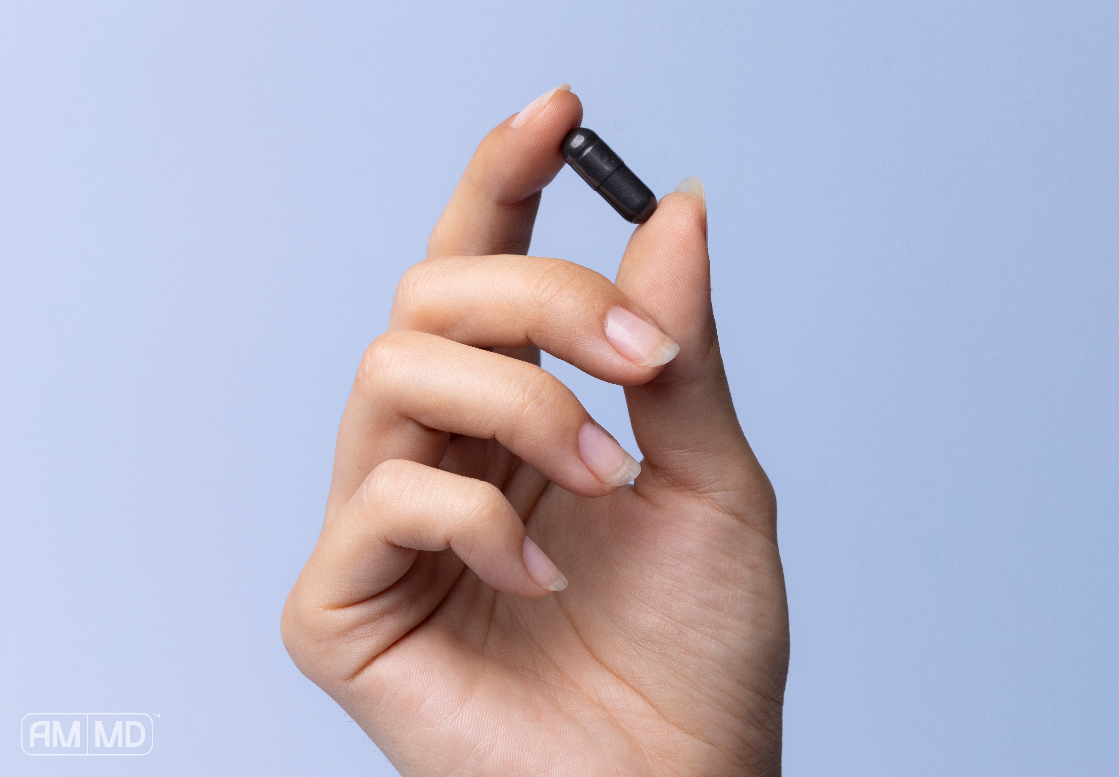 Holding a capsule of activated charcoal - 5 Activated Charcoal Benefits for Adults - AMMD™