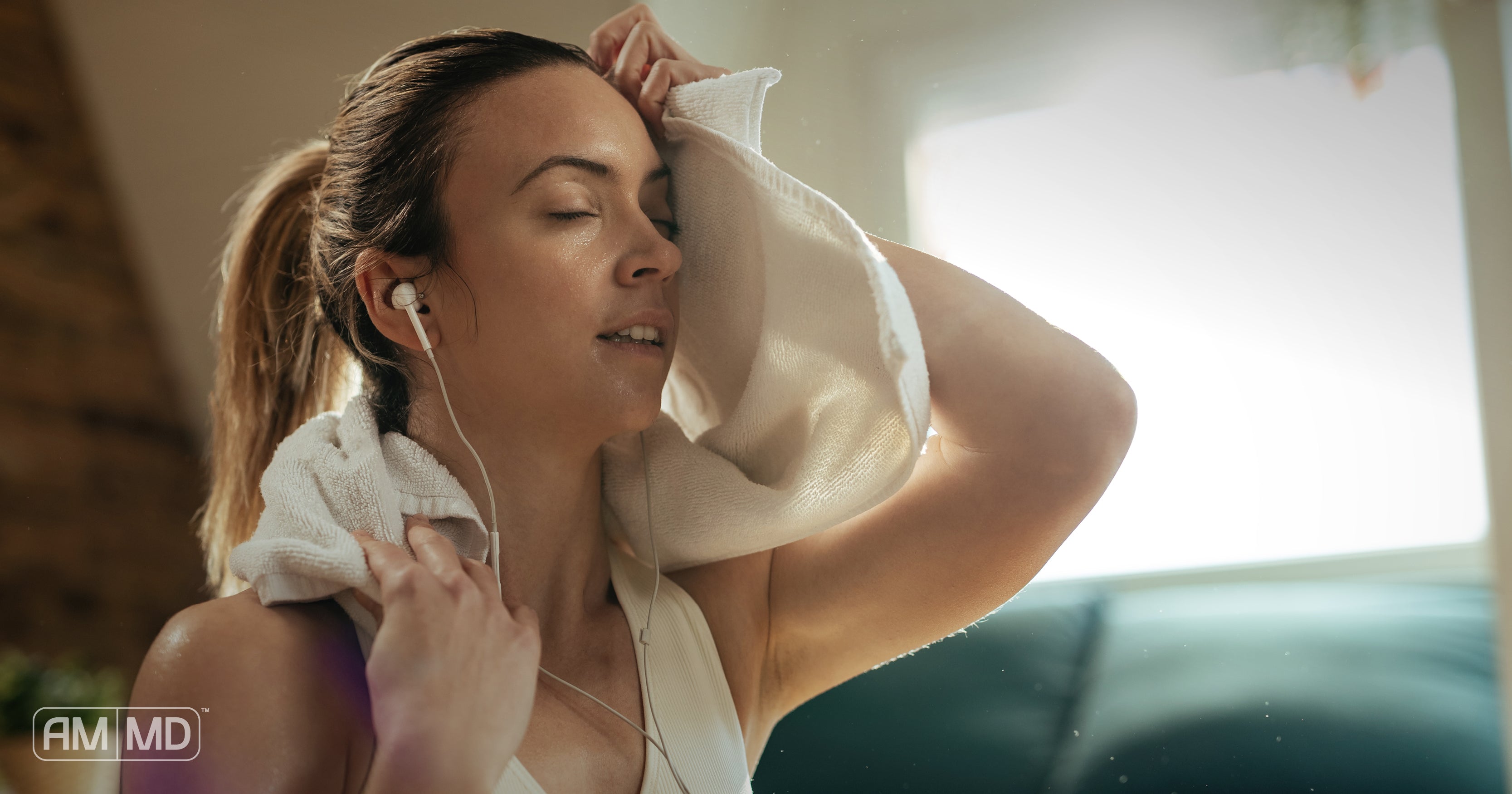 Woman patting head with towel after workout - The Benefits of Sweating - AMMD™