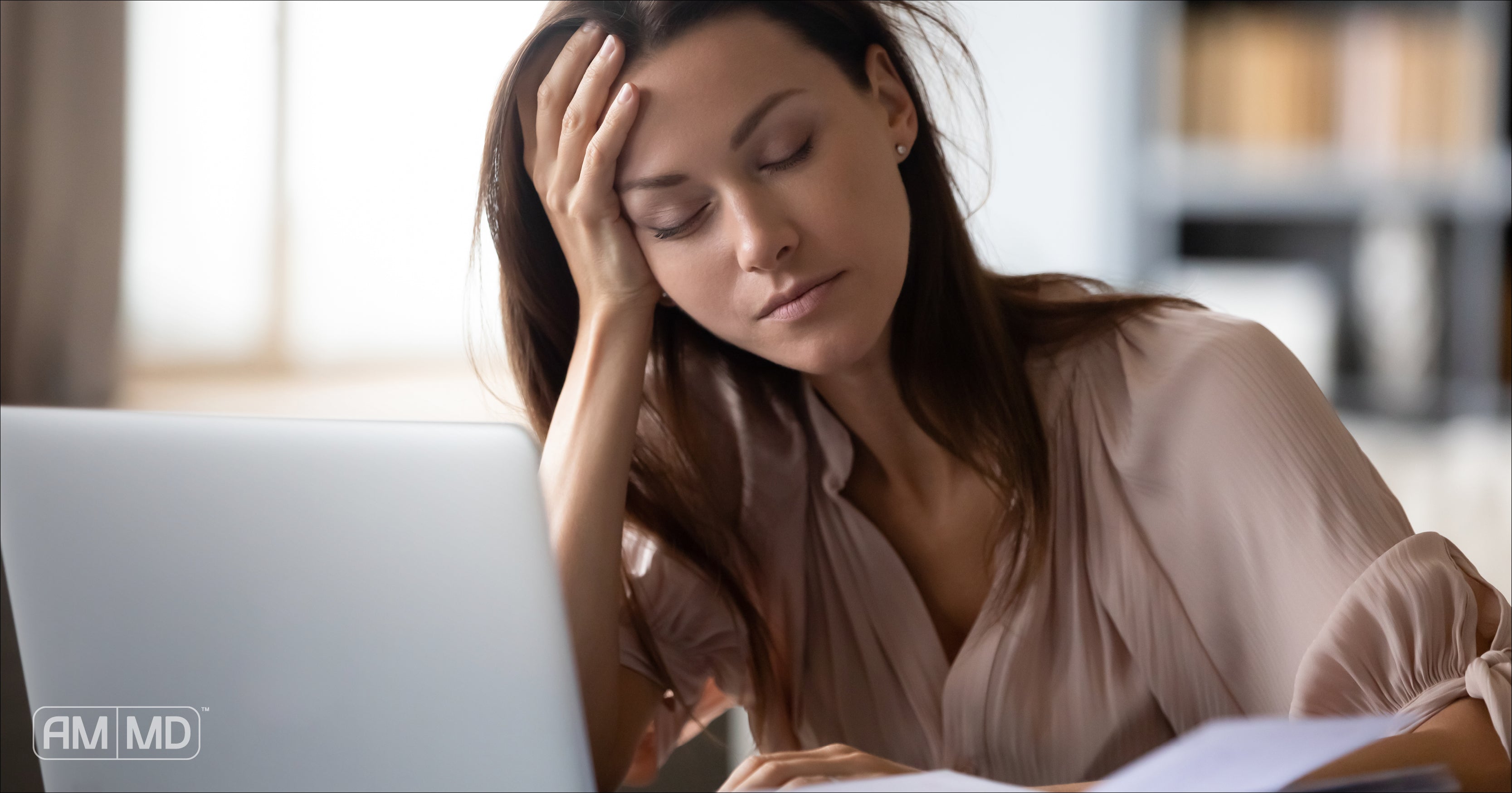 Woman resting head in hand in front of computer - What Is Causing Your SIBO Relapse? - AMMD™