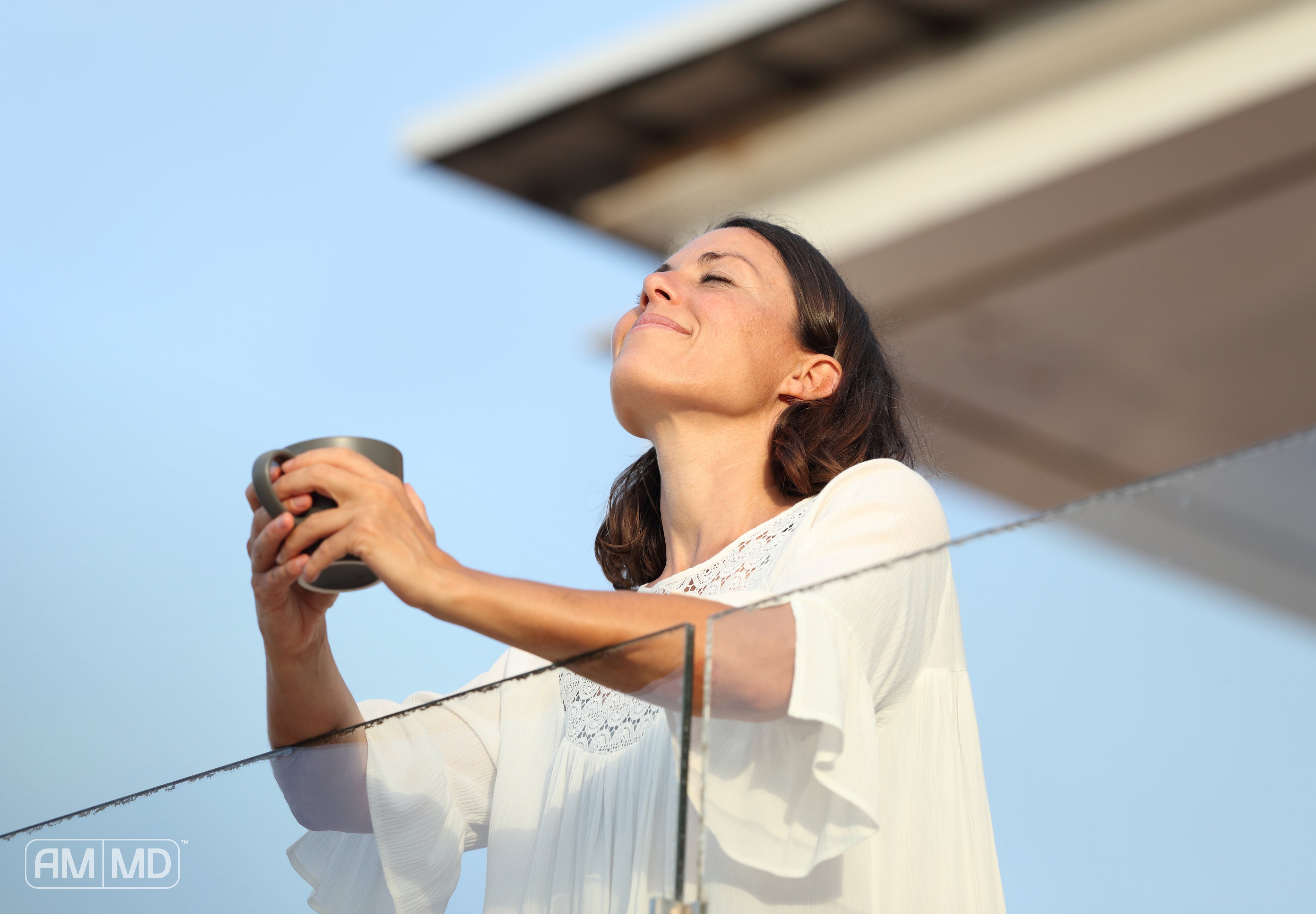 Woman sitting coffee outside on a balcony - What to Take for Energy: Full-Body Approach - AMMD™