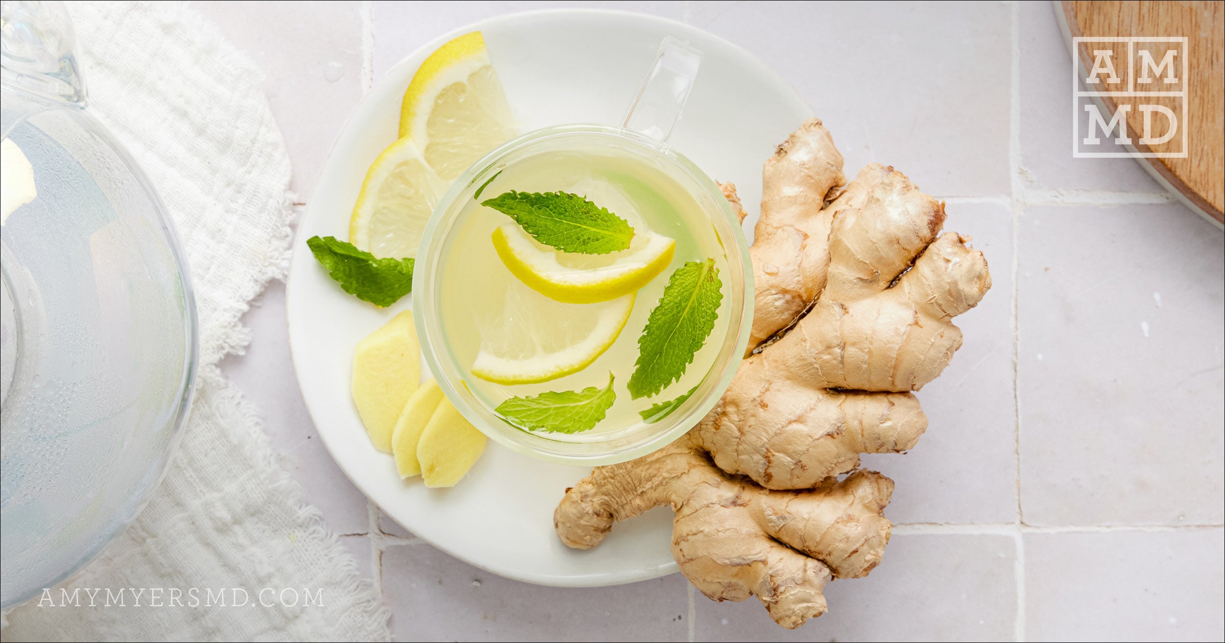 A cup of Ginger Mint Tea garnishes with lemon, mint leaves, and ginger root - Amy Myers MD®