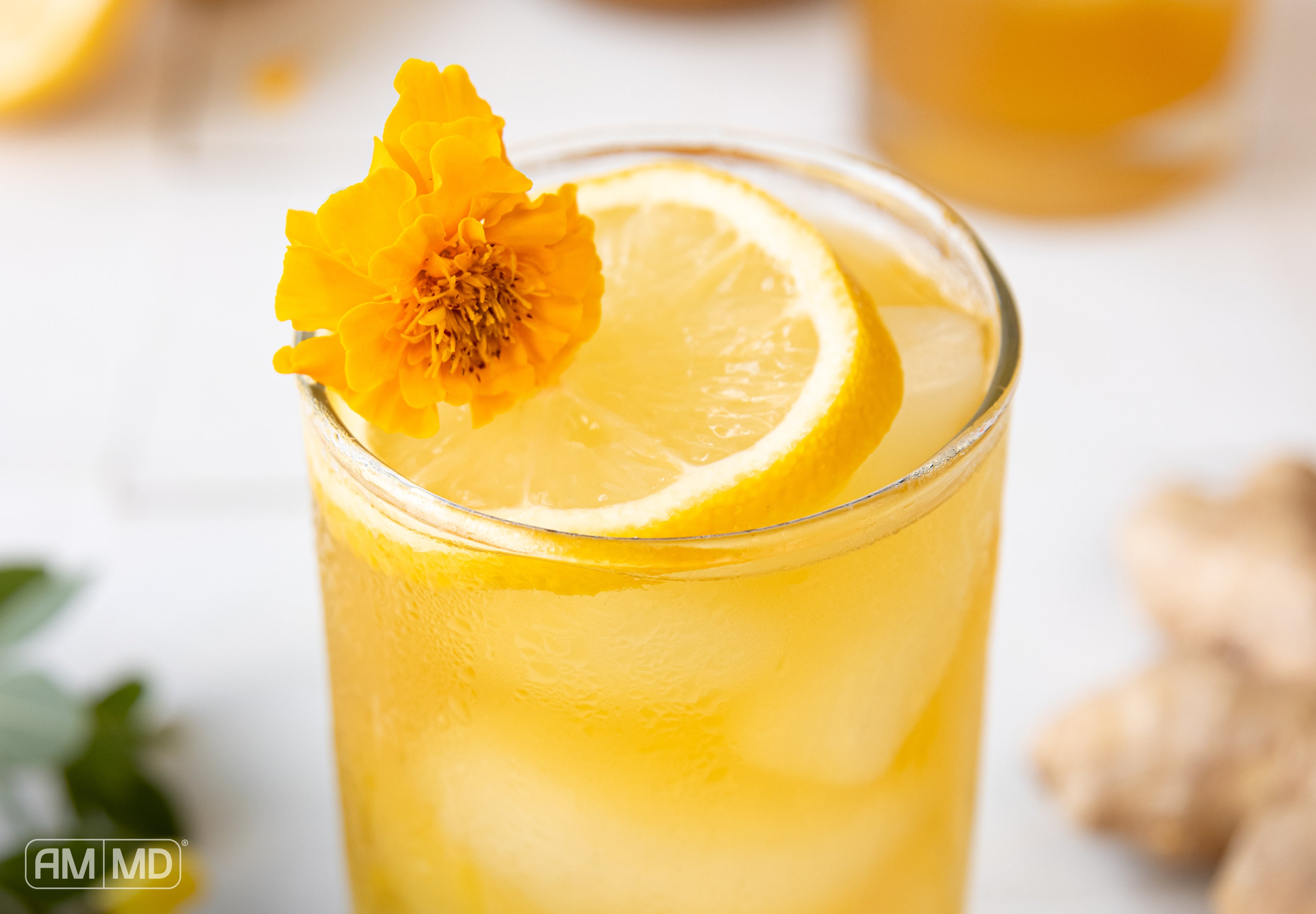 Turmeric and ginger iced tea served over ice with fresh lemon and edible flowers for a refreshing gut-support beverage
